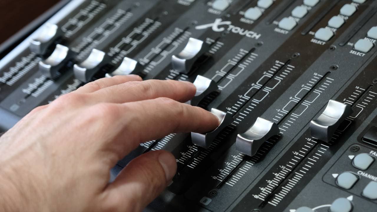 Hands on mixing console faders at Tuba Sessions
